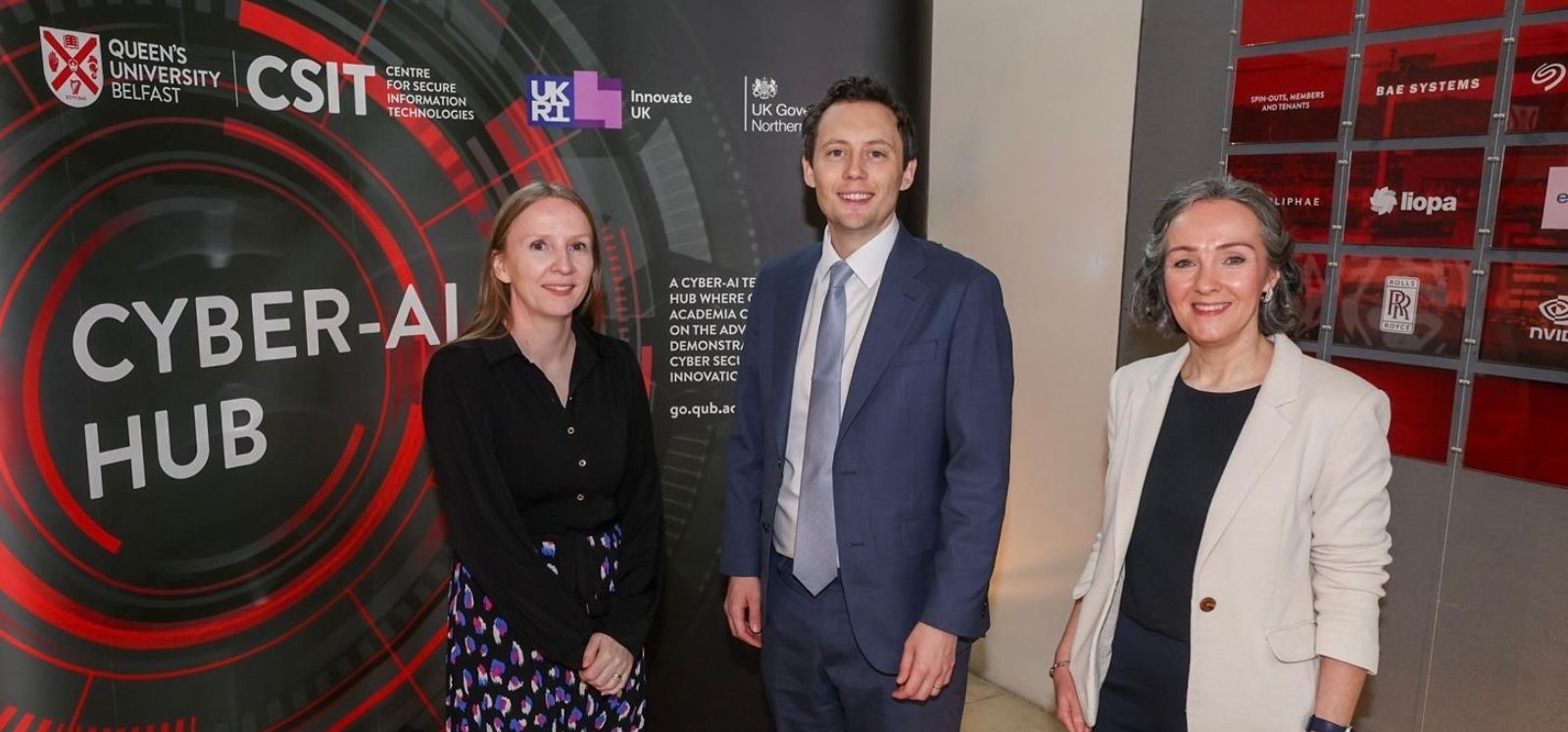 Minister Patrick, Máire O'Neill and Judith Millar standing in front of a CSIT Cyber-AI Hub Sign in the Foyer of CSIT